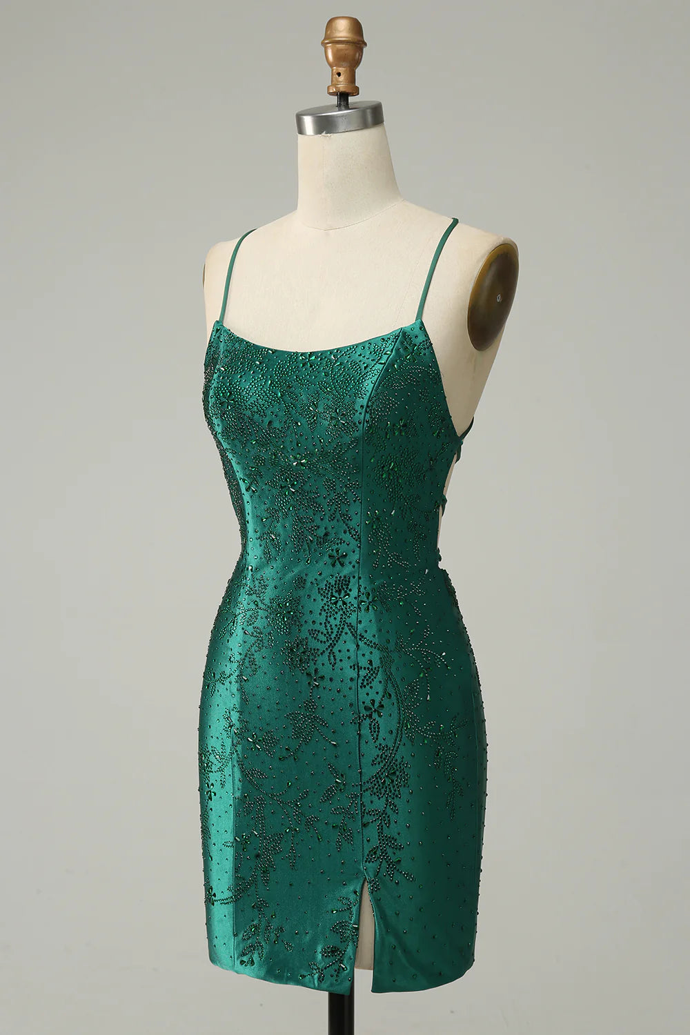 Model wearing a dark green beaded bodycon mini dress, back view, highlighting the criss-cross straps.
