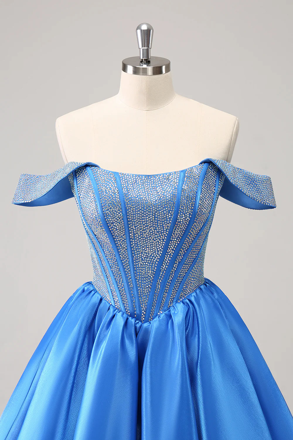 Close-up of intricate beading and luxurious satin fabric on blue dress.