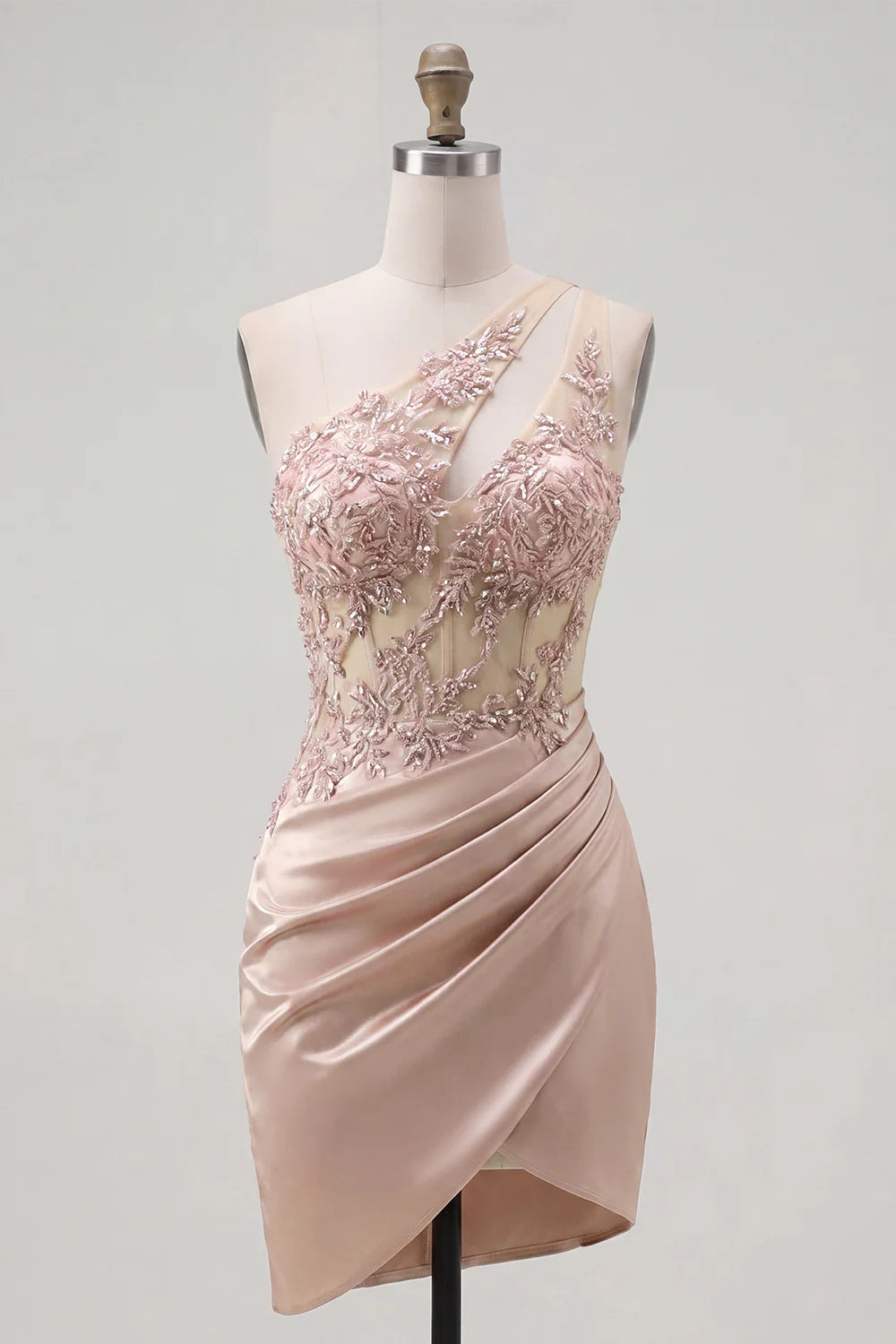 Model in a blush pink one-shoulder dress, showing the lustrous satin fabric and mini length.