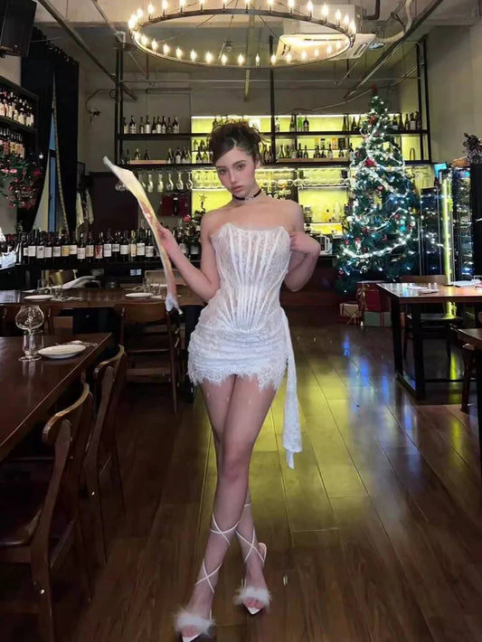 Model in Koutun strapless bodycon mini homecoming dress with lace corset and asymmetrical hem.