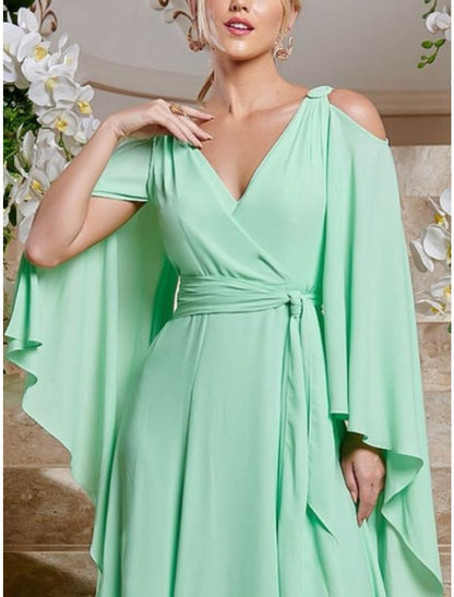 Side profile of a woman wearing a long sleeve V-neck chiffon dress, highlighting the column silhouette.