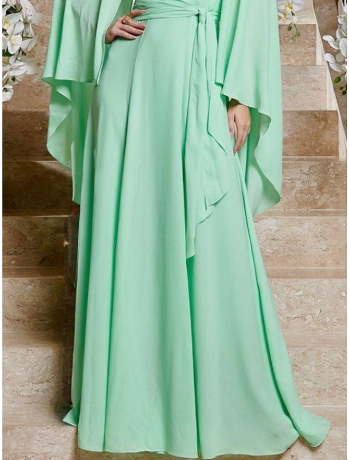 Close-up of the pleated and ruffled details on the elegant chiffon wedding guest dress.