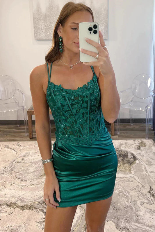 Model wearing an emerald green bodycon homecoming dress with leaf appliques and spaghetti straps.