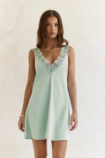 Close-up of the V-neckline and lace trim detail on the sage green dress.