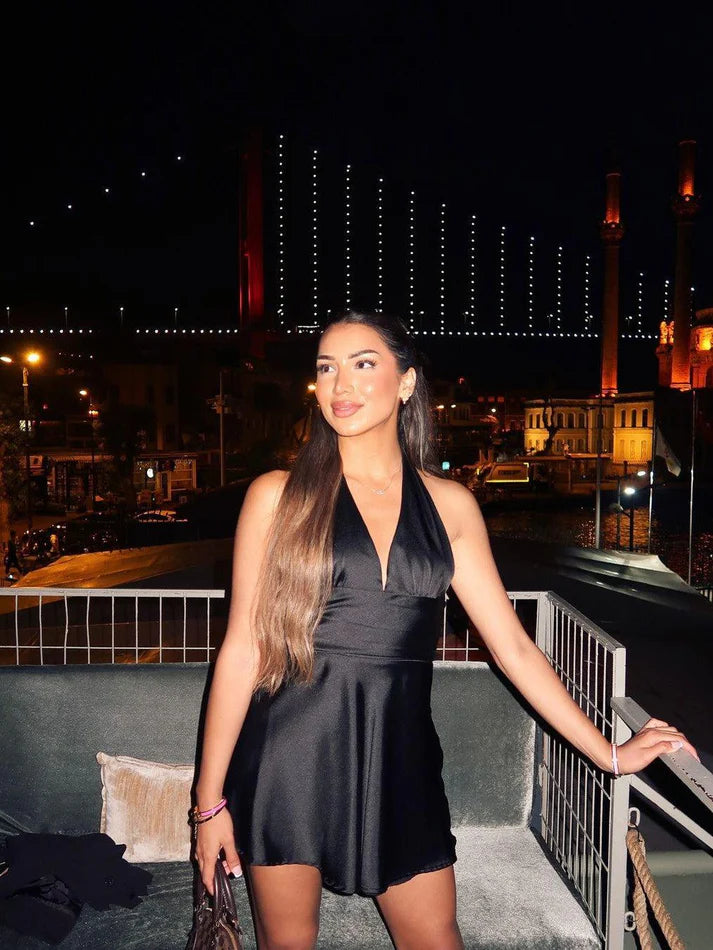 Model posing in the halterneck deep V-neck mini homecoming dress.