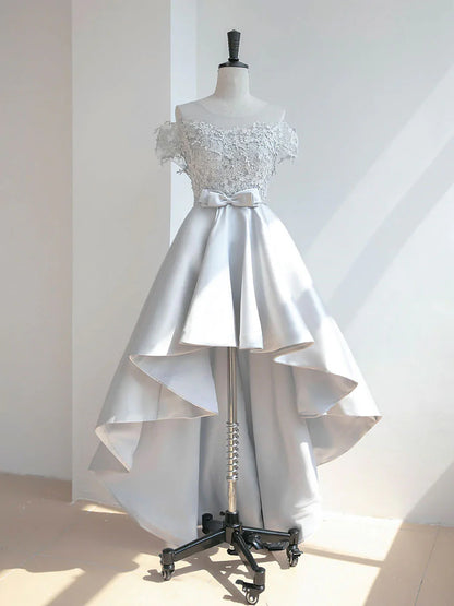 A woman wearing an elegant high-low lace satin prom dress with a scoop neckline.
