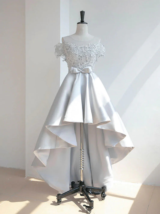 A woman wearing an elegant high-low lace satin prom dress with a scoop neckline.