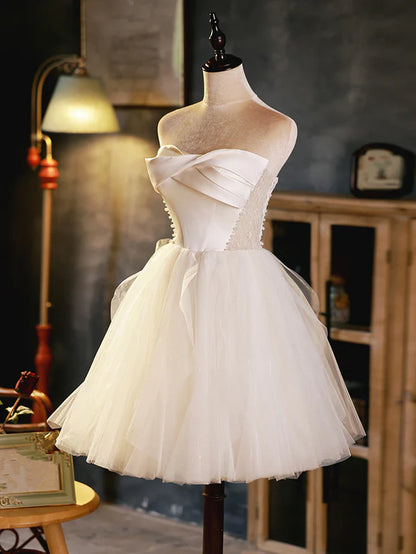 Side profile of the ivory homecoming dress, highlighting the satin bodice and flowing tulle.