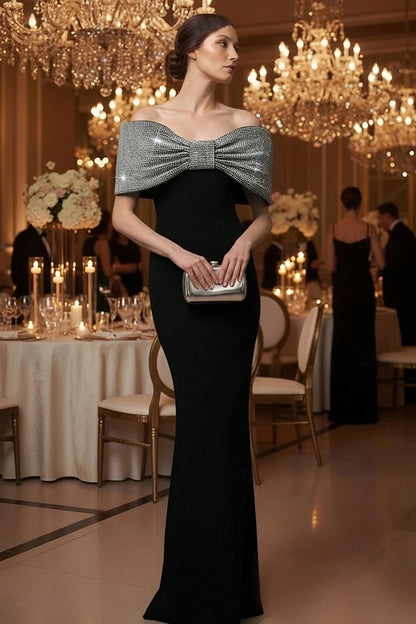 Model wearing Koutun black off-shoulder mermaid dress with beaded bow, front view.