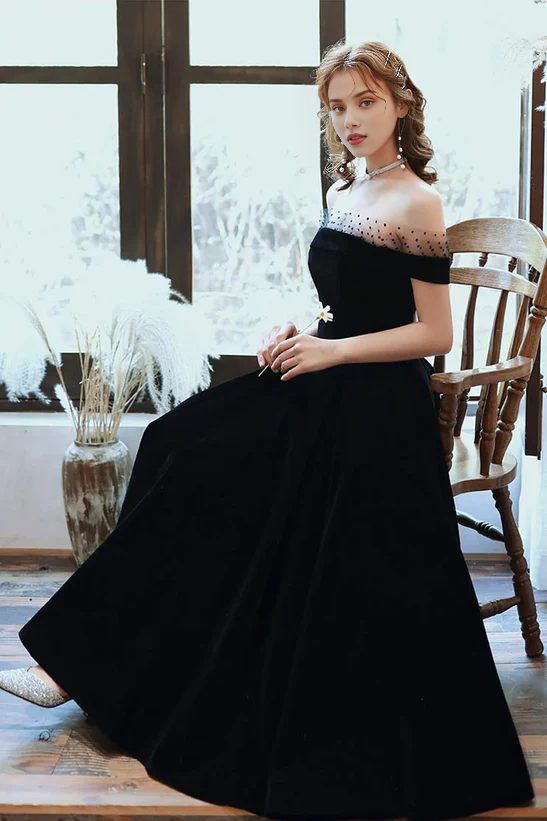 Side profile of a woman in the black off-shoulder velvet party gown.