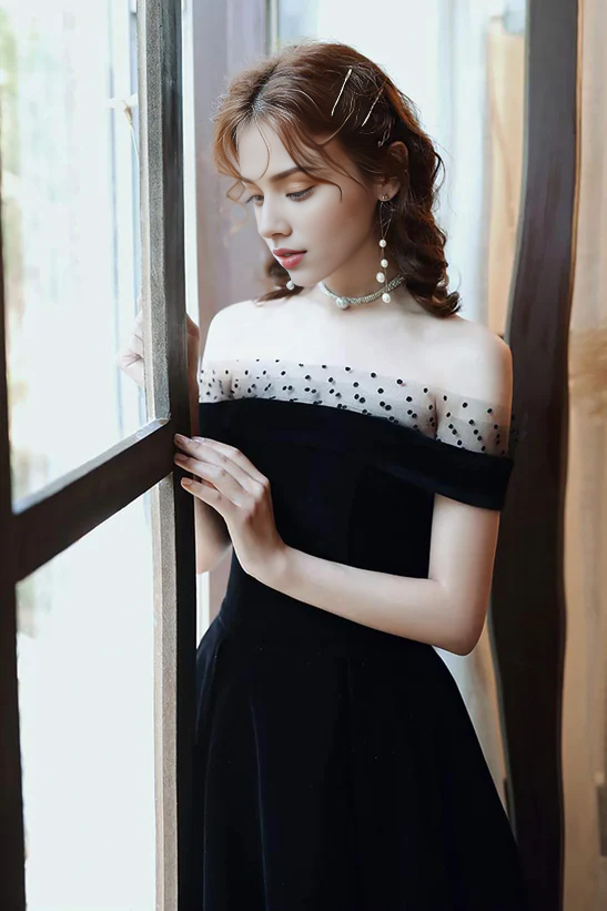 Close-up of the off-shoulder neckline and velvet fabric of the black dress.