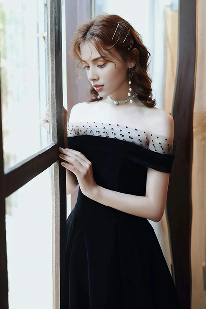 Close-up of the off-shoulder neckline and velvet fabric of the black dress.