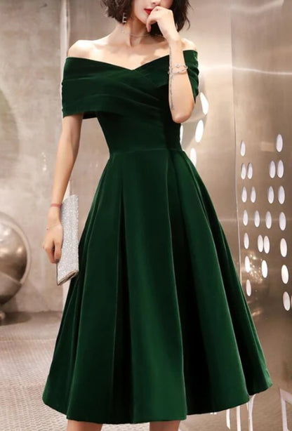 Back view of a model in a green velvet off-shoulder dress.