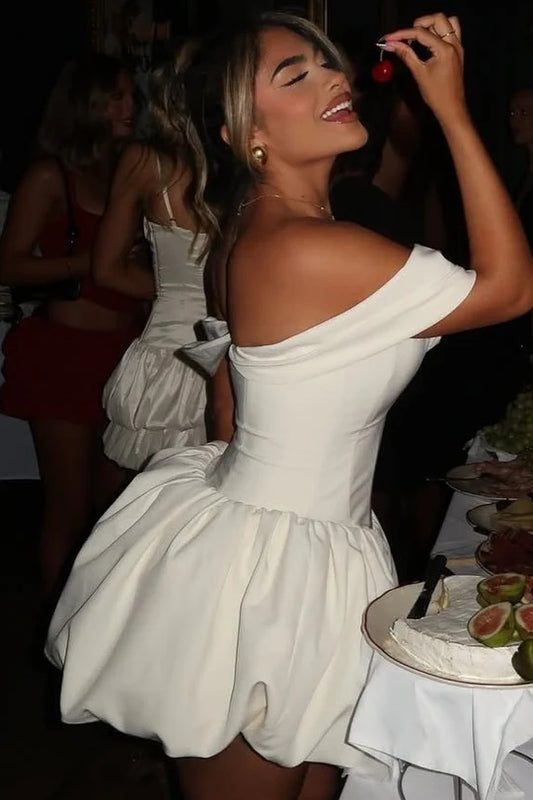 Model wearing an elegant white satin cocktail dress with off-shoulder V-neckline.