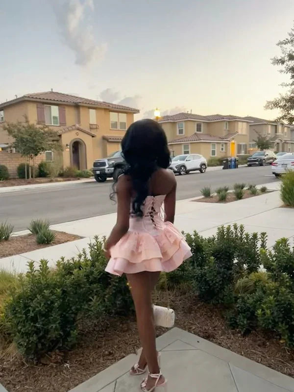 Model posing in pink strapless corset dress.