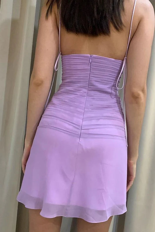 Model wearing a pleated bodycon mini homecoming dress with spaghetti straps, side view.