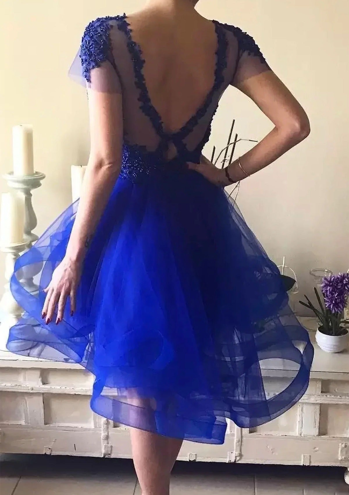 Back view of royal blue A-line high-low homecoming dress with layered tulle skirt.