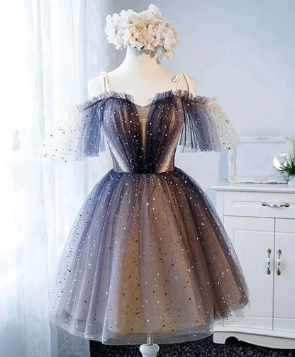 Model wearing a short V-neck tulle and lace prom dress with spaghetti straps.