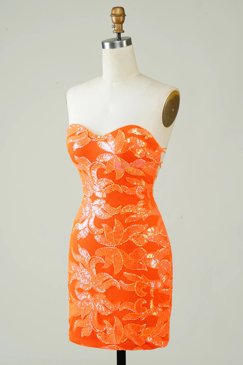 Side profile of a model in an orange strapless formal dress.