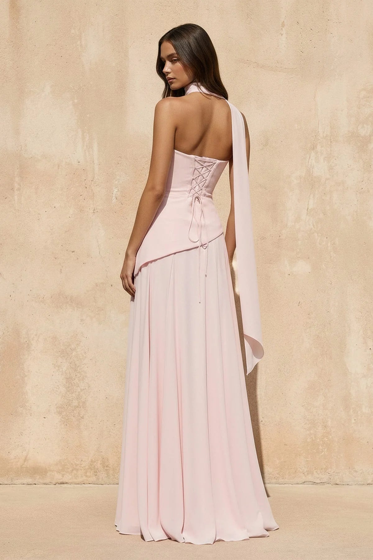 Back view of a Koutun strapless formal gown showing the lace-up corset detail.