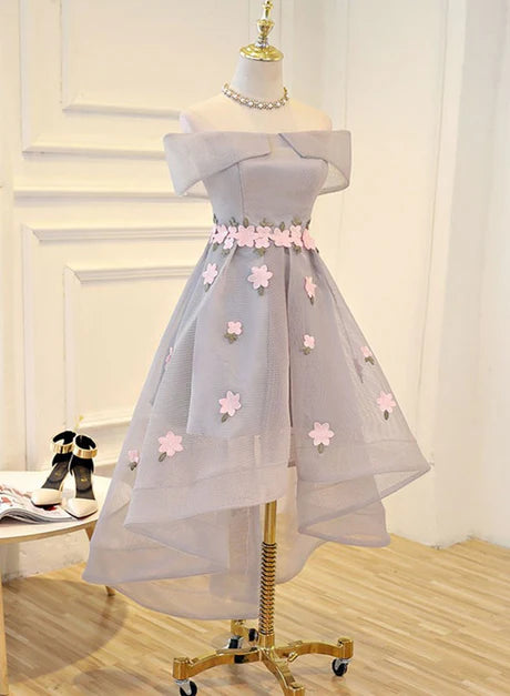 Model wearing a light grey high-low tulle dress with floral details.