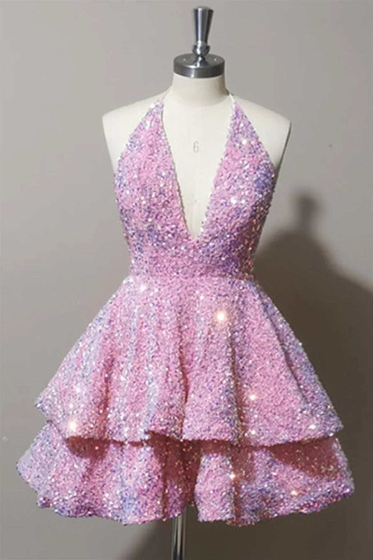 Model wearing a pink tiered sequin short homecoming dress with a deep V-neck and halter neckline.