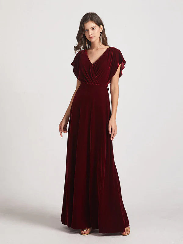 Woman wearing a V-neck flutter sleeve velvet bridesmaid dress with an open back.