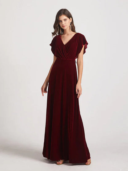 Woman wearing a V-neck flutter sleeve velvet bridesmaid dress with an open back.