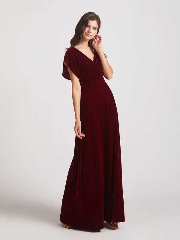 Side view of a woman posing in a velvet bridesmaid dress with flutter sleeves.