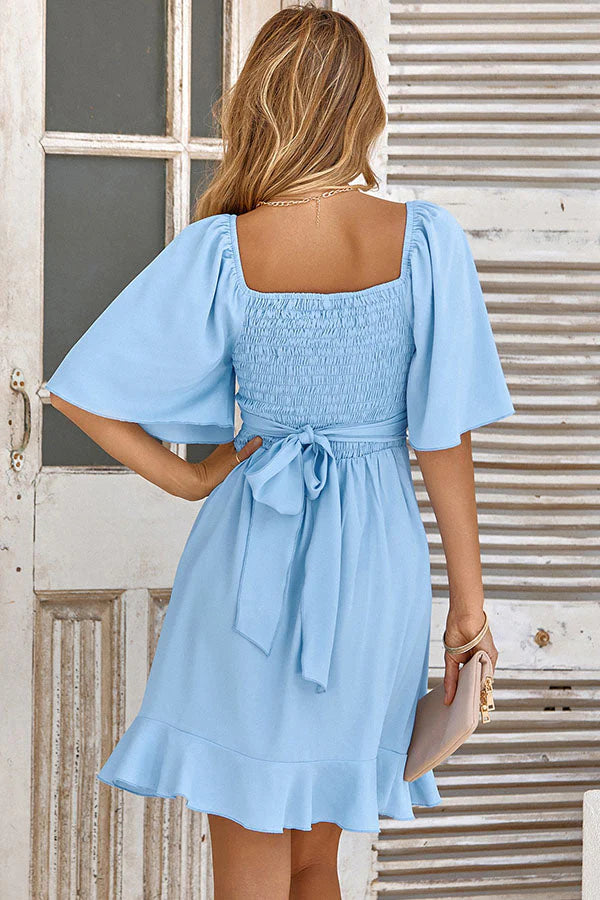 Back view of a solid color V-neck ruffled waist mini dress.