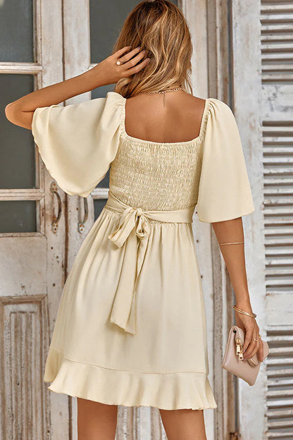 Full length view of the solid color V-neck ruffled waist mini dress.