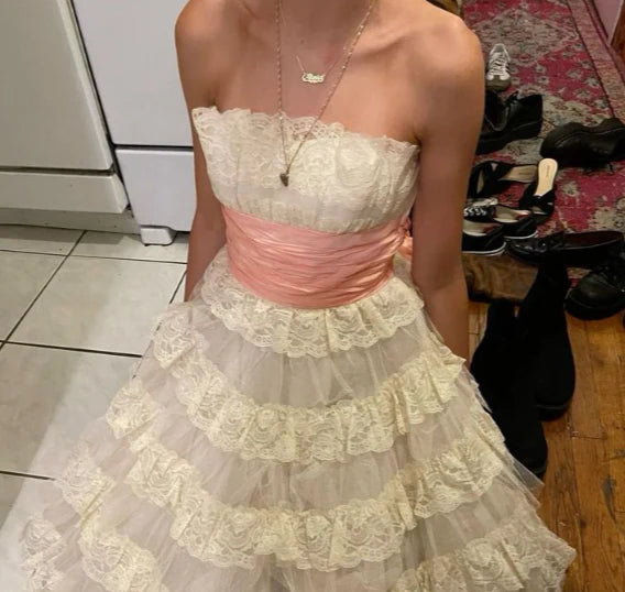 Contrast waist sash and delicate lace fabric on a vintage-inspired dress.