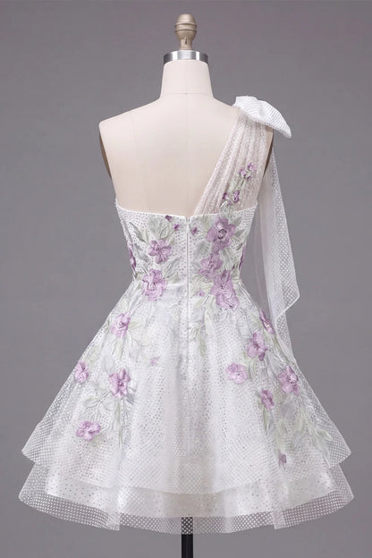 Detail of the large sheer bow on the one-shoulder neckline of the white dress.