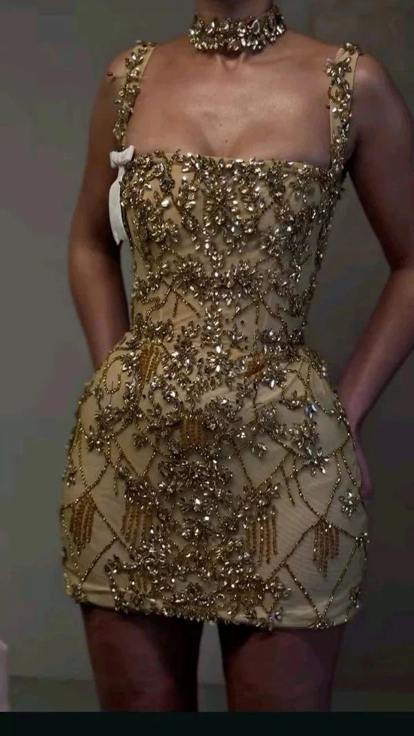 Model wearing a glamorous nude mesh mini bodycon dress with square neck, gold beads, and crystal embellishments.