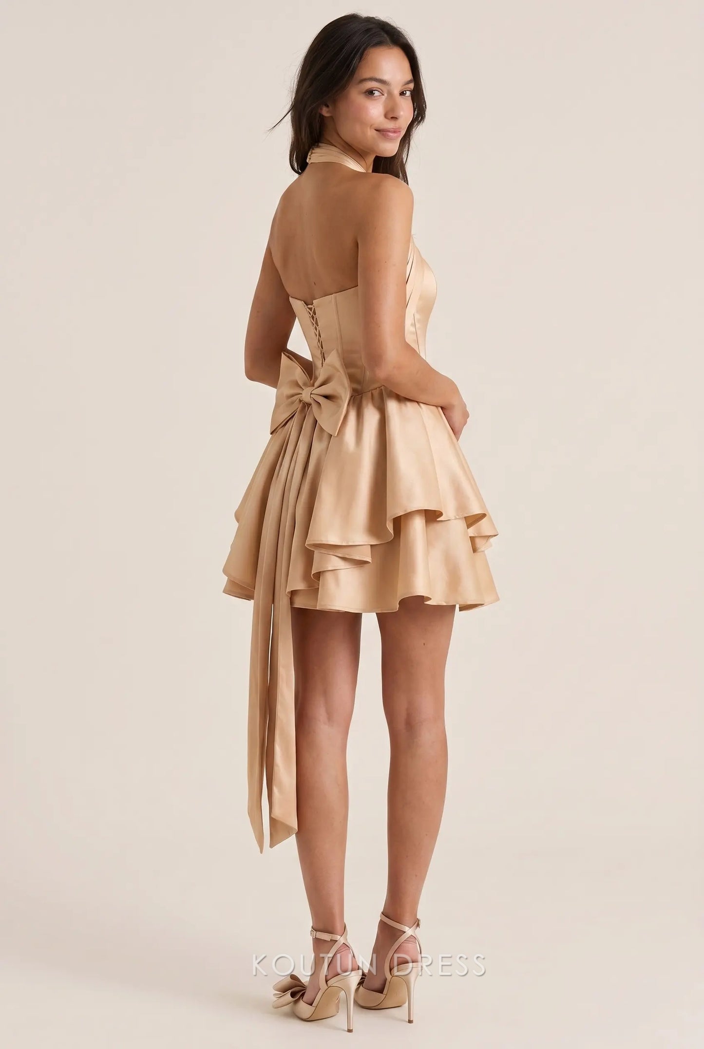 Back view of the Koutun halter neck corset satin mini dress showing lace-up detail and large bow.