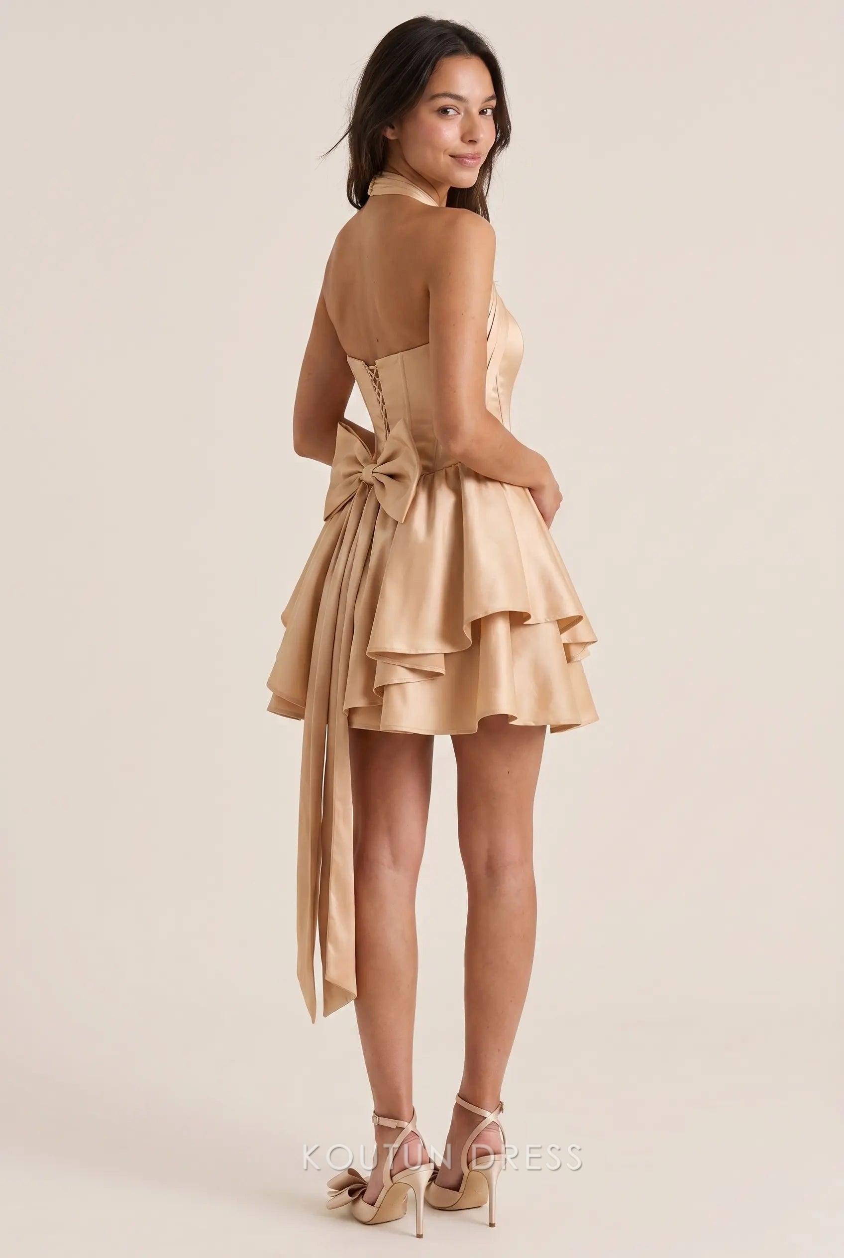Back view of the Koutun halter neck corset satin mini dress showing lace-up detail and large bow.