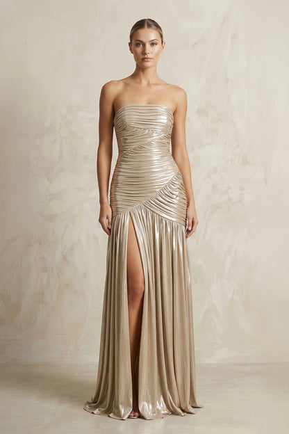 Model in strapless ruched metallic jersey gown with high slit.