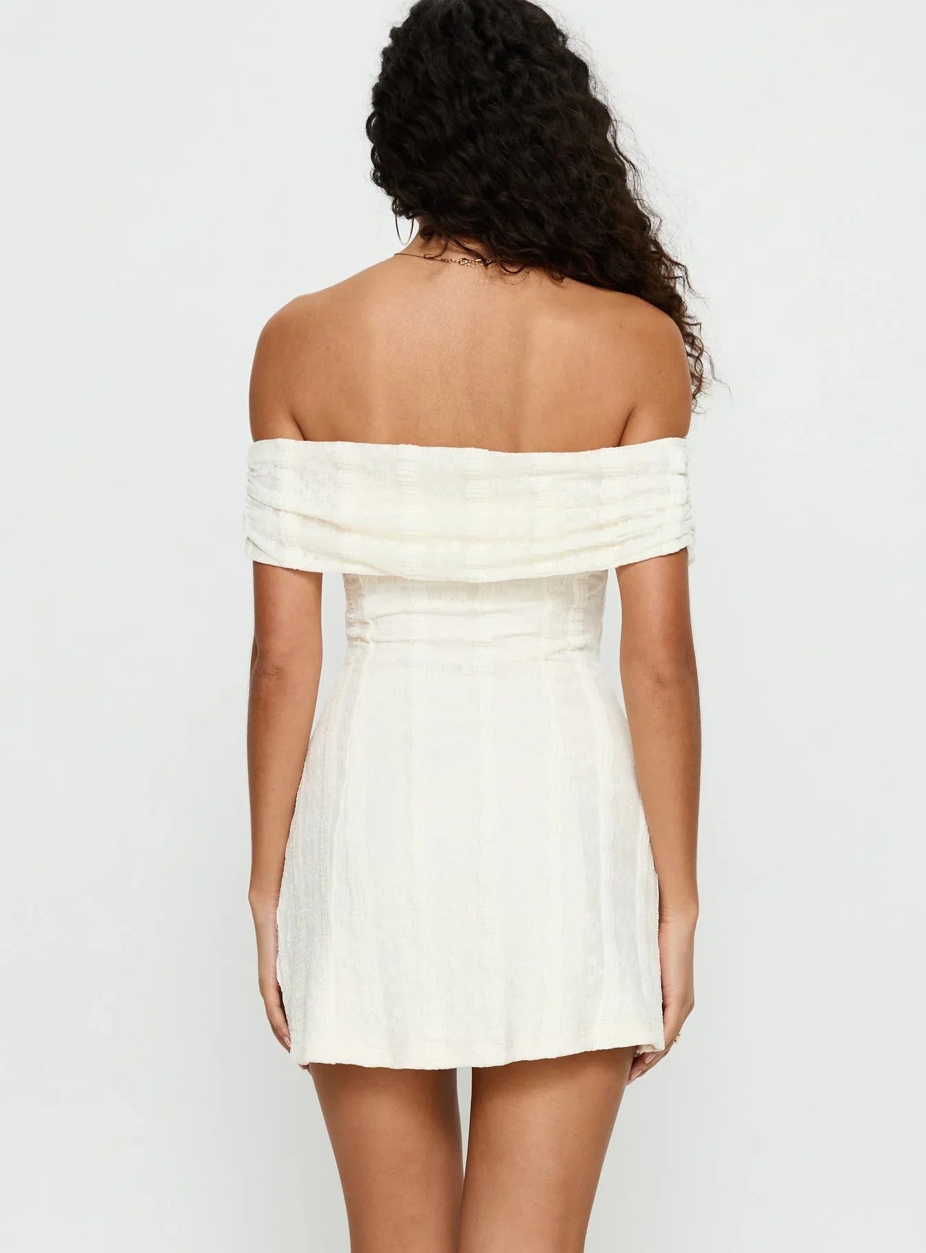 Back view of the cream off-shoulder mini dress, highlighting textured fabric.