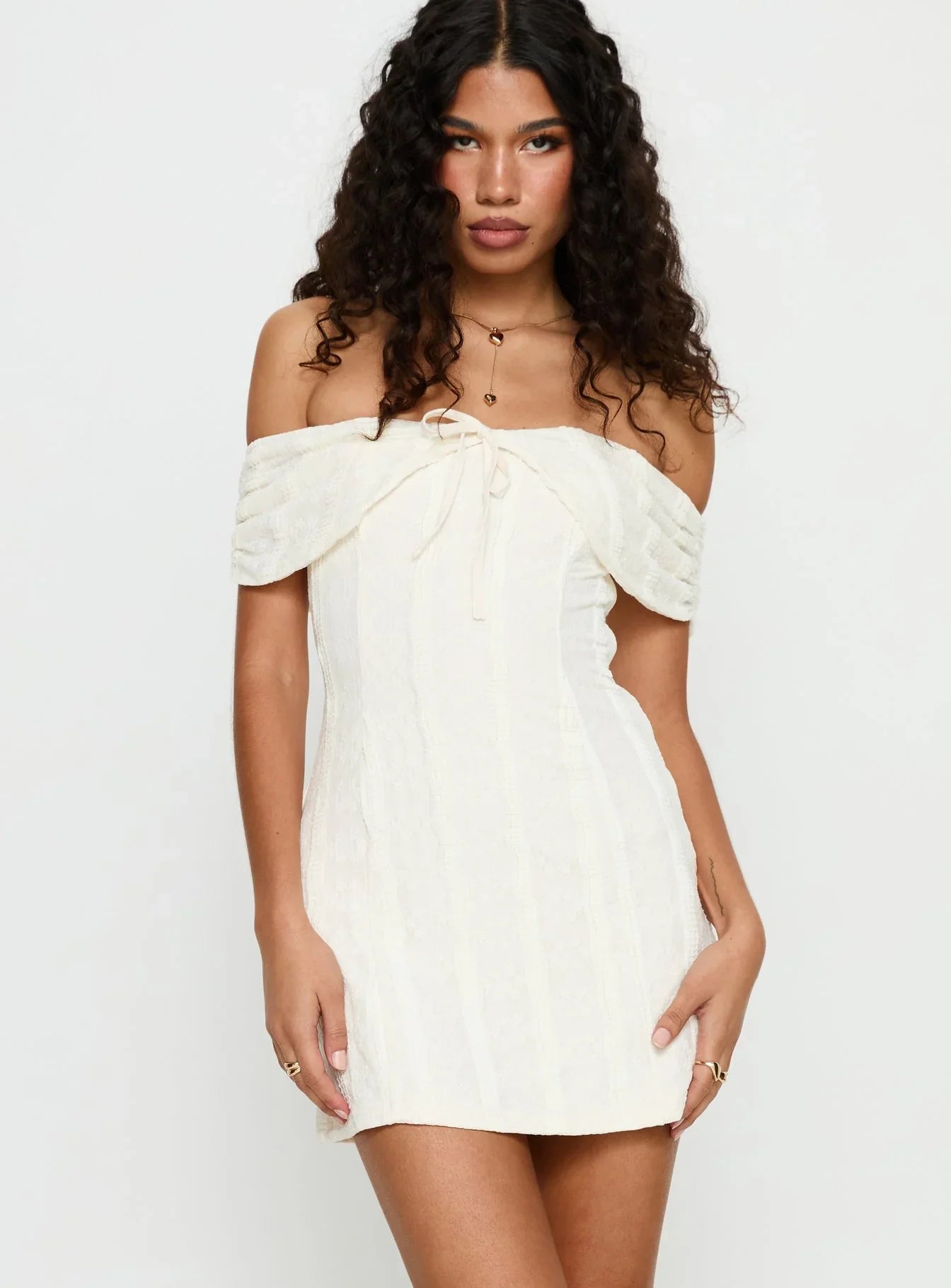 Close-up of the bow detail on the cream off-shoulder dress.