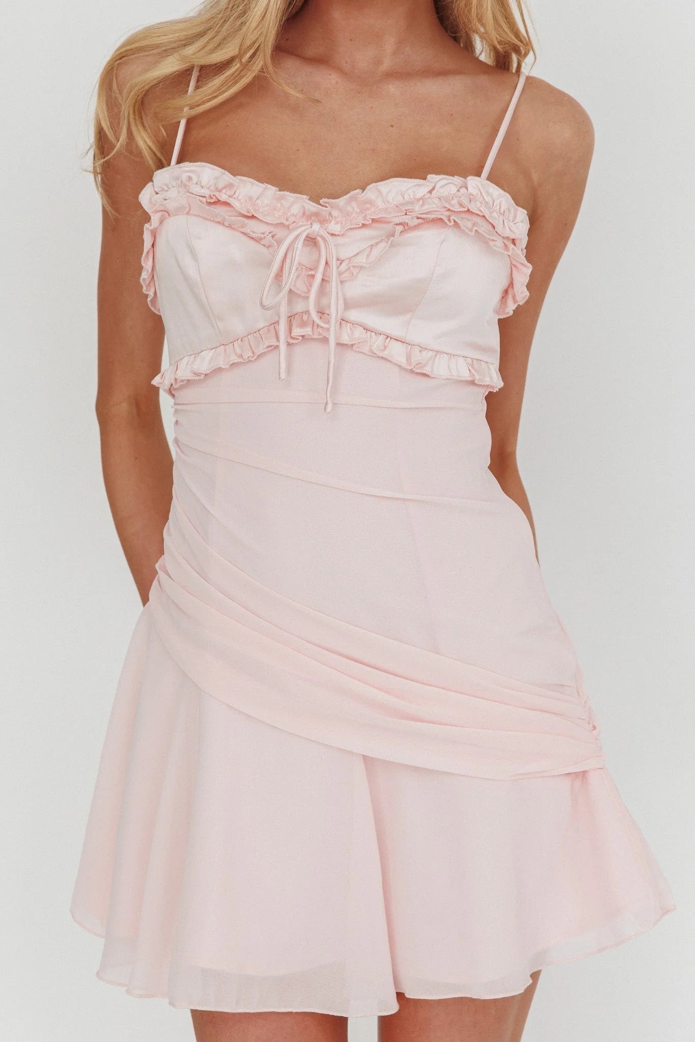 Close-up of the ruffled sweetheart neckline and spaghetti straps on the pink dress.