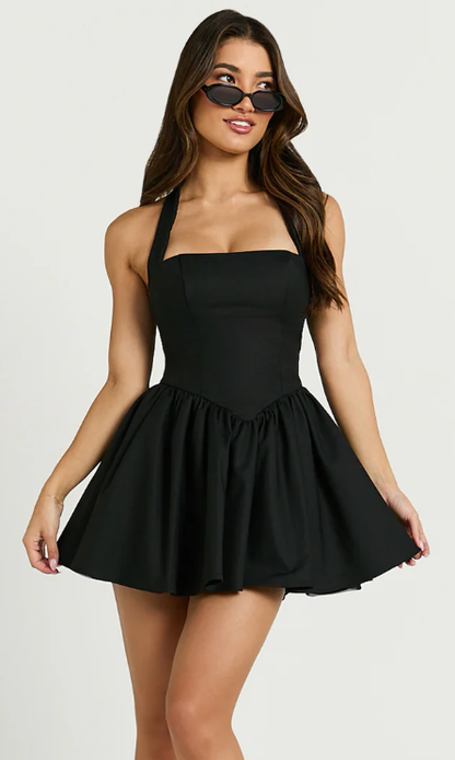 Woman in a black halter tie neck corset panel dress, seated pose.