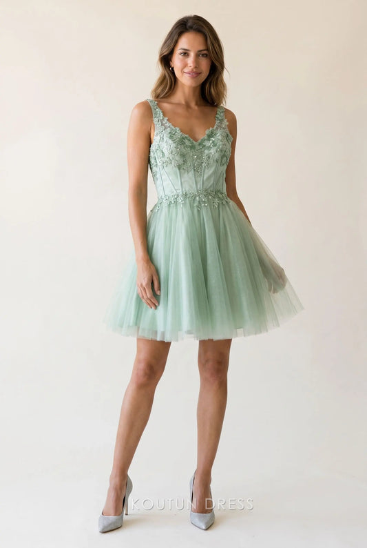 Model wearing a sage green glitter tulle mini homecoming dress with a V-neck and floral lace applique.