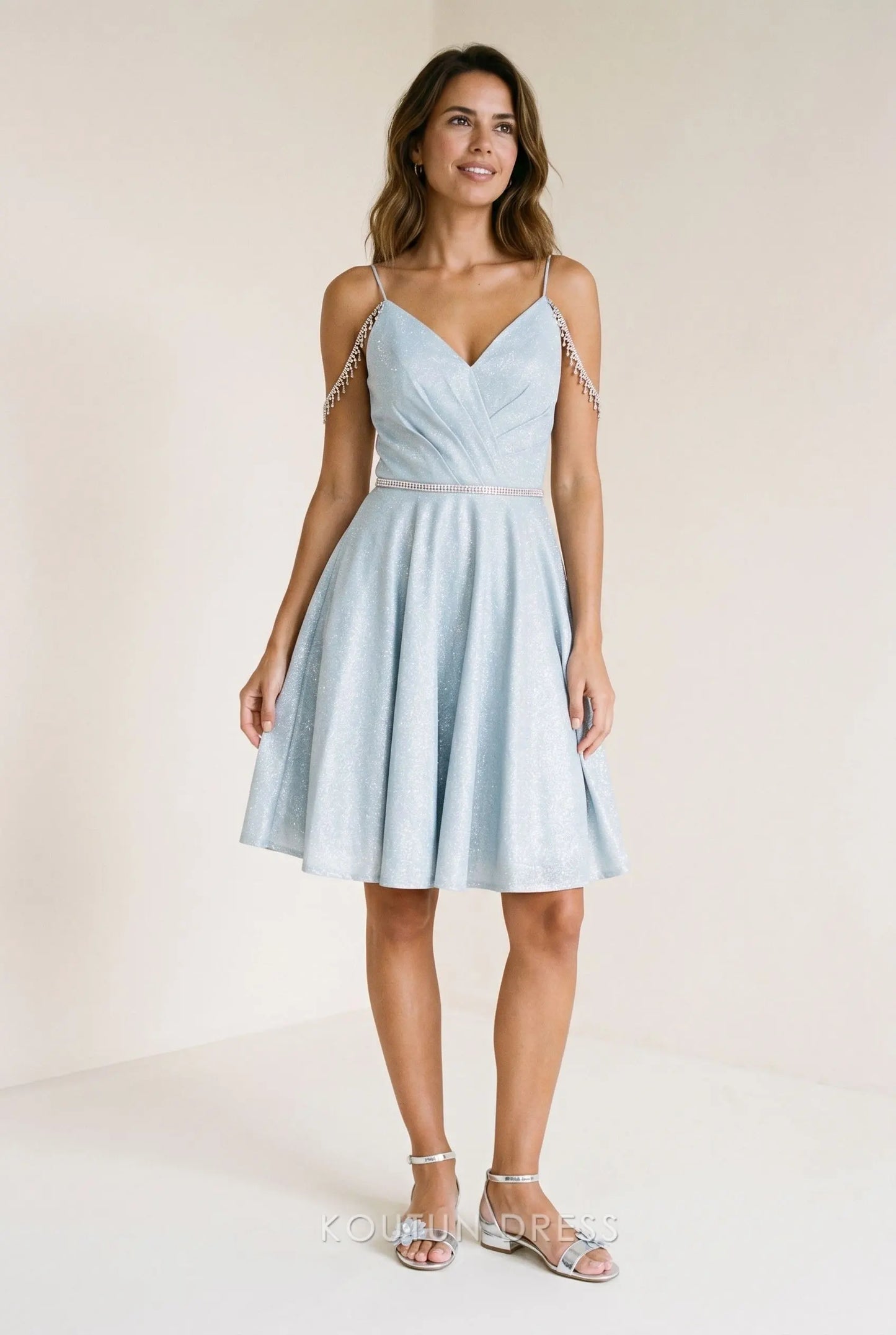 Model in ice blue glitter satin mini homecoming dress with deep V-neck and rhinestone fringe.