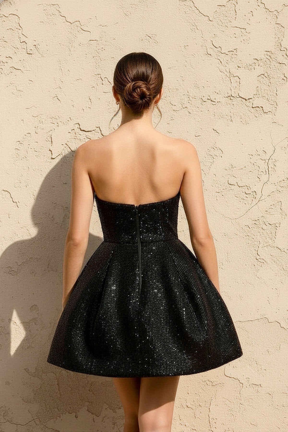 Model wearing Koutun strapless sequin mini dress, full length.
