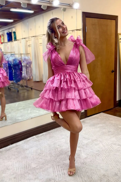 Back view of a model in a sparkling A-line tiered short homecoming dress with a bow.