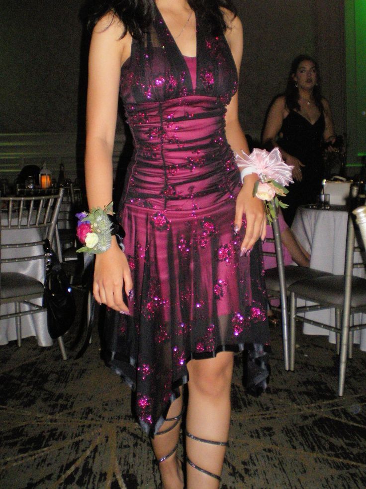 Model wearing a black and magenta glitter floral short homecoming dress with a halter neck and ruched mesh bodice.