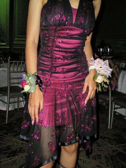 Side view of a model in the black and magenta glitter floral short homecoming dress, highlighting the asymmetrical hem.