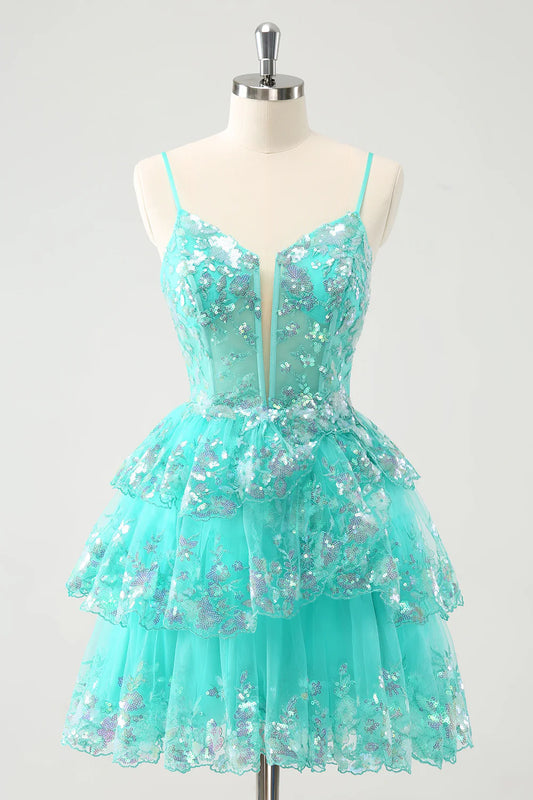 Model wearing a sparkly green A-line tiered sequin homecoming dress with spaghetti straps.