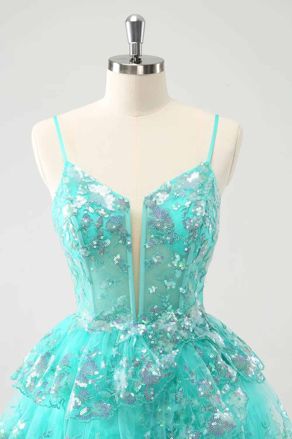 Close-up of the shimmering green sequin embellishments on the tiered fabric.