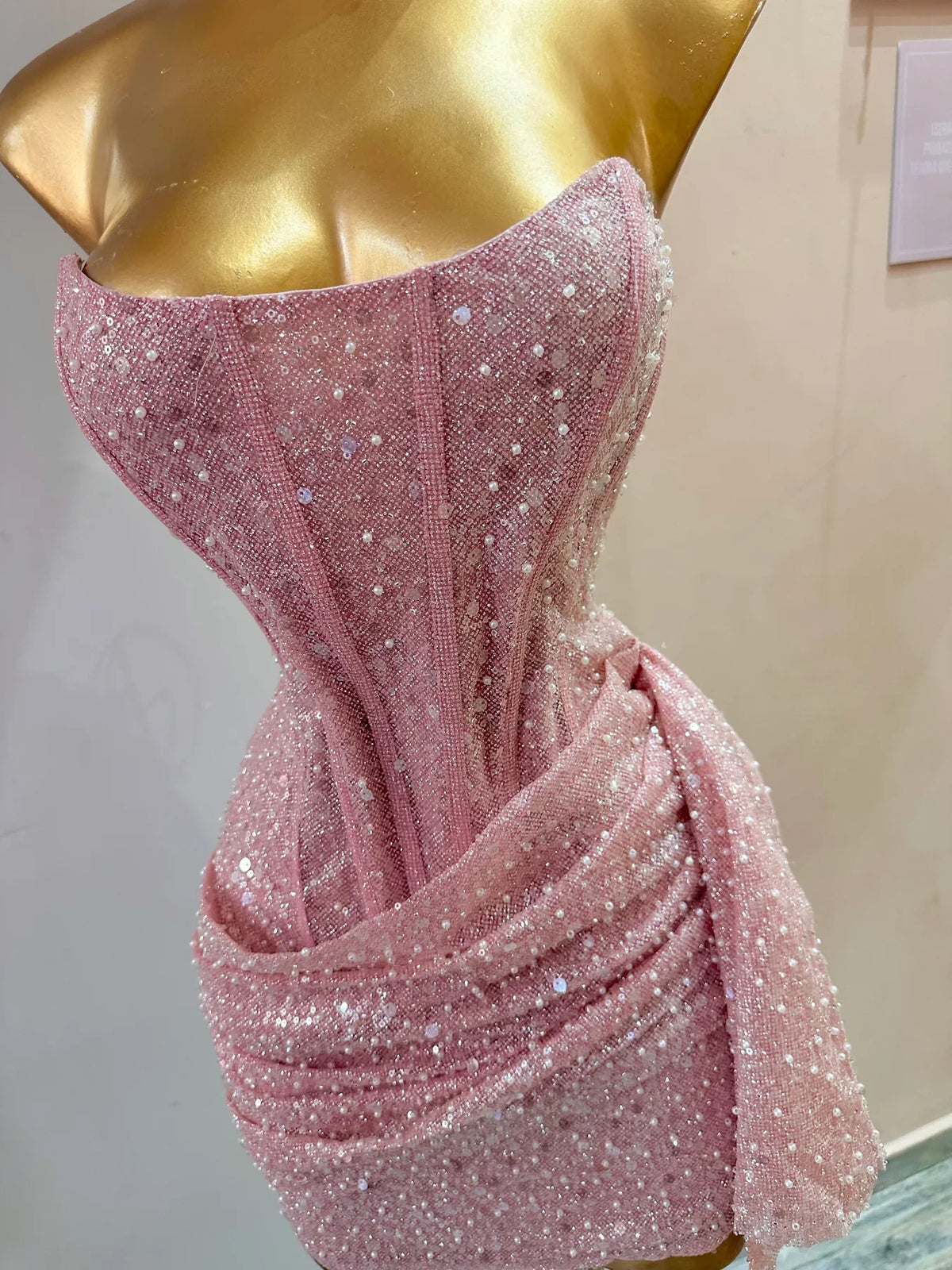 Full-length view of the pink strapless sequin dress with a side-draped skirt.